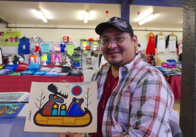 Gull Bay artist Kevin Belmore with his animal protest painting that features a group of animals leaving in a canoe over man’s destruction of the environment.  Photo by Rick Garrick